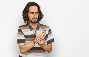 Günlük kıyafetler giyen genç İspanyol adam ellerinde ve parmaklarında ağrı, eklem iltihabı 