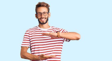 Sarışın, sakallı, sıradan kıyafetler giyen, el kol hareketleri yapan, iri ve büyük beden işareti olan, ölçü sembollü yakışıklı bir adam. Kameraya bakıp gülümsüyor. ölçüm kavramı. 