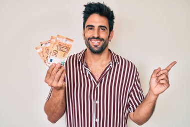 Avro banknotları tutan yakışıklı, sakallı, mutlu, eli ve parmağı kenarda gülümseyen bir İspanyol. 