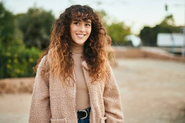 Genç İspanyol kadın gülümseyerek şehirde mutlu mesut dikiliyor.