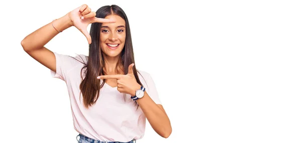 カジュアルな白いTシャツを着た若いヒスパニック系の女性は 幸せな顔で手や指でフレームを作り笑顔 創造性と写真の概念 — ストック写真