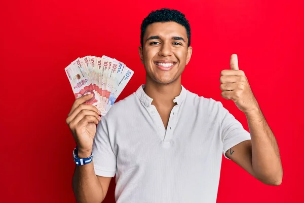Joven Árabe Sosteniendo Pesos Colombianos Sonriendo Feliz Positivo Pulgar Hacia —  Fotos de Stock