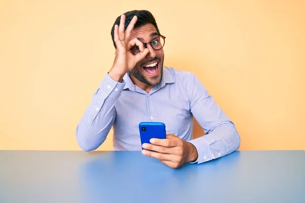 Hombre Hispano Joven Usando Teléfono Inteligente Sentado Mesa Sonriendo Feliz —  Fotos de Stock