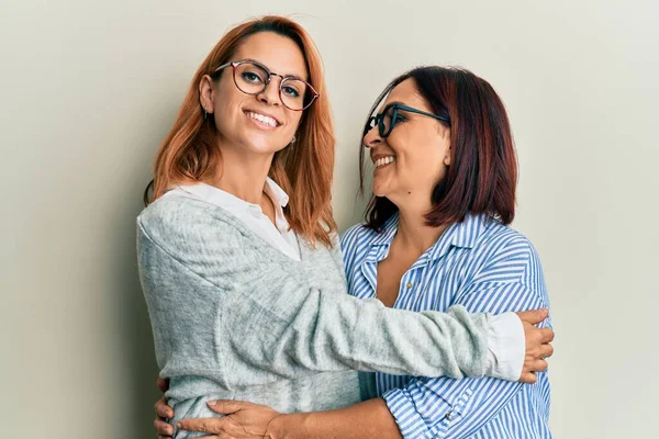 西班牙裔母亲和女儿高兴地微笑着 拥抱着孤零零的白人背景 — 图库照片