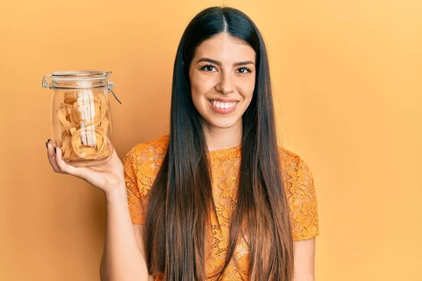 Junge Hispanische Frau Hält Glas Mit Ungekochten Nudeln Und Schaut — Stockfoto