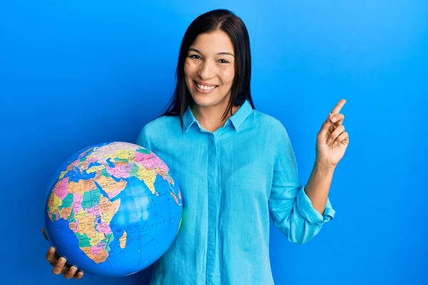 Young Latin Woman Holding Big World Ball Smiling Happy Pointing — ストック写真