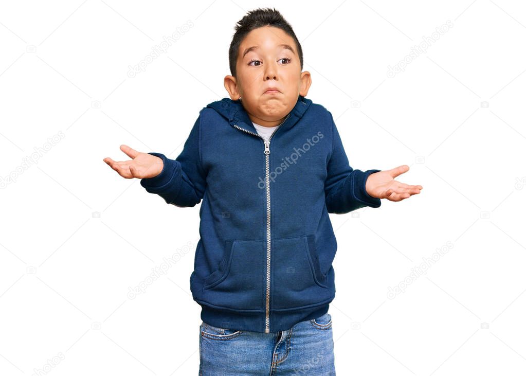 Little boy hispanic kid wearing casual sporty jacket clueless and confused expression with arms and hands raised. doubt concept. 