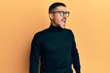 Balıkçı yaka kazak giyen, kızgın ve kızgın gözlüklü sinirli sinirli sinirli ve öfkeyle bağıran yakışıklı bir adam. öfke ve agresif konsept. 