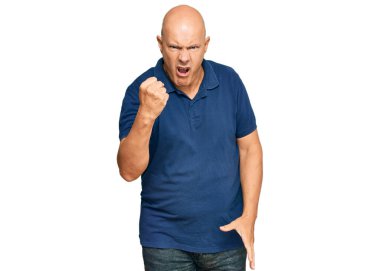 Orta yaşlı, kel bir adam, kızgın ve kızgın. Öfkeyle bağırırken yumruğunu kaldırıyor. öfke ve agresif konsept. 