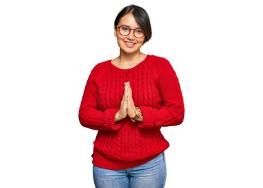 Kısa saçlı, sıradan bir süveter giyen ve gözlüklü genç ve güzel bir İspanyol kadın ellerinin altında dua ederek af diliyor kendinden emin bir şekilde gülümseyerek.. 