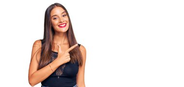 Gündelik kıyafetler giyen, neşeli, yüzünde bir gülümseme olan genç İspanyol kadın mutlu ve doğal bir ifadeyle elini ve parmağını kaldırdı. 