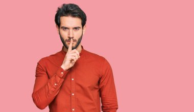 Gündelik kıyafetler giyen genç İspanyol adam parmakları dudaklarında sessiz olmak istiyor. sessizlik ve gizli konsept. 