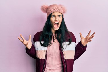 Kışlık yün kazak giyen, şapkalı, deli deli deli bağıran, agresif ifade ve kollarıyla bağıran genç İspanyol kadın. hüsran kavramı. 