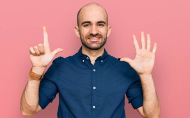 Gündelik kıyafetler giyen genç İspanyol adam yedi numarayı gösterip işaret ederken kendinden emin ve mutlu bir şekilde gülümsüyor.. 