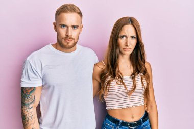 Genç bir çift kız arkadaş ve erkek arkadaş birbirine sarılıyor ve yan yana duruyorlar şüpheci ve gergin, sorun yüzünden suratları asık. negatif kişi. 