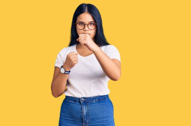 Genç, güzel Asyalı bir kız, günlük kıyafetler ve gözlük takıyor. Yumruk savunma hareketiyle dövüşmeye hazır. Kızgın ve üzgün bir yüz, sorundan korkuyor. 