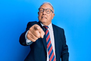 İş elbisesi ve kravat takan kıdemli beyaz adam kameraya kızgın ve sinirli bir şekilde bakıyor. 