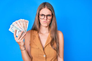 Birleşik Krallık 'ı elinde tutan genç sarışın kız şüpheci ve gergin, sorun yüzünden üzgün. negatif kişi. 