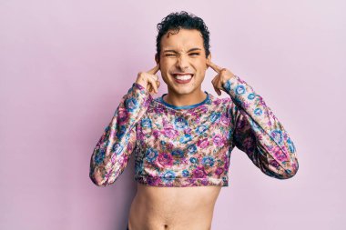 Makyaj yapan yakışıklı bir adam yüksek sesli müzik sesi için kulaklarını parmaklarıyla kapatıyor. sağır kavramı. 