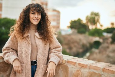 Genç İspanyol kadın gülümseyerek şehirde mutlu mesut dikiliyor.