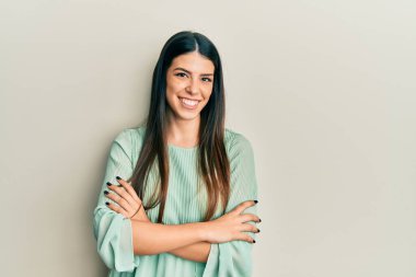 Gündelik kıyafetler giyen, kollarını kavuşturup kameraya gülümseyen genç İspanyol kadın. pozitif kişi. 