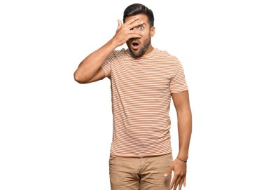 Yakışıklı İspanyol bir adam, günlük giysiler giymiş. Şoka girmiş, yüzünü ve gözlerini kapamış, utanmış bir ifadeyle parmaklarından bakıyor.. 