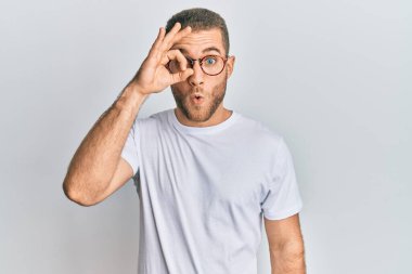 Gündelik giysiler ve gözlük takan genç beyaz adam şaşırmış yüz ve gözlerle parmaklarından bakıyor. İnançsız ifade. 