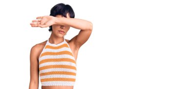 Kısa saçlı, esmer, sıradan kıyafetler giyen, gözlerini kollarıyla kapatan, ciddi ve üzgün görünen genç bir kadın. Görme, saklama ve reddetme konsepti 