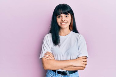 Gündelik kıyafetler giyen, kollarını kavuşturup kameraya gülümseyen genç İspanyol kız. pozitif kişi. 