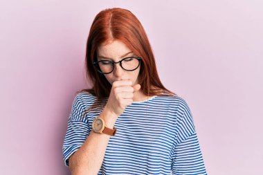 Sıradan kıyafetler ve gözlük takan genç kızıl saçlı kız kendini iyi hissetmiyor ve soğuk algınlığı veya bronşitin belirtisi olarak öksürüyor. sağlık hizmeti kavramı. 