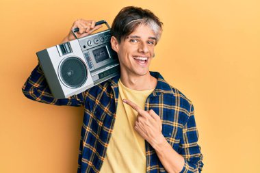 Kasetçalar tutan genç İspanyol adam, müzik dinliyor, gülümsüyor, mutlu bir şekilde işaret ediyor. 