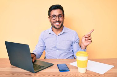 Ofiste çalışan genç İspanyol bir adam bir fincan kahve içip gülümsüyor. 