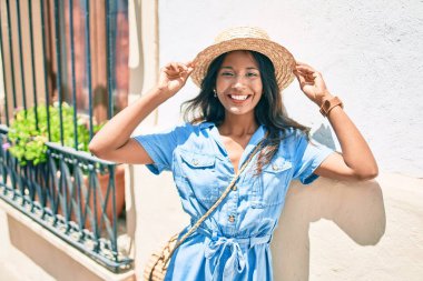 Genç, güzel Hintli bir kadın duvara yaslanıyor ve gülümsüyor..