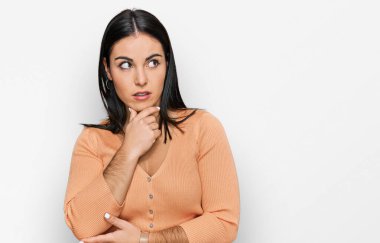 Gündelik giysiler giyen genç İspanyol kadın bir soru hakkında endişeli ve gergin bir şekilde düşünüyor. 