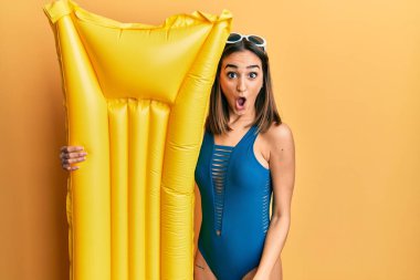 Genç esmer kız mayo giyiyor ve elinde yaz şamandırası var. Korkmuş ve ağzı açık kalmış, şaşırmış, inançsız bir yüz. 