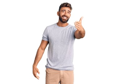 Gündelik kıyafetler giyen genç İspanyol adam dostça bir selamlama ve hoş geldin hediyesi olarak el sıkışmayı sunuyor. başarılı iş. 