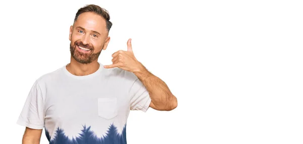 カジュアルなタイ染料のTシャツを着たハンサムな中年の男性は 電話で話すような手や指で電話のジェスチャーをして笑顔 コミュニケーションの概念 — ストック写真