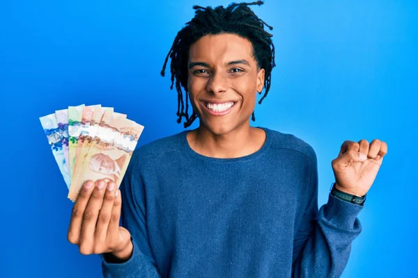 Νεαρός Αφροαμερικάνος Που Κρατάει Καναδικά Δολάρια Ουρλιάζοντας Περήφανος Γιορτάζοντας Νίκη — Φωτογραφία Αρχείου