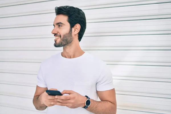 若いヒスパニック男笑顔幸せな使用スマートフォンで市 — ストック写真