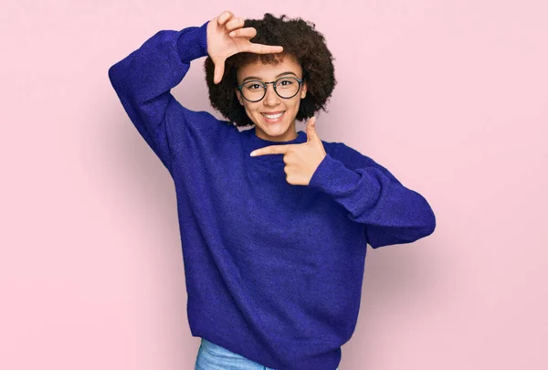 カジュアルな冬のセーターと眼鏡を身に着けている若いヒスパニック系の女の子は幸せな顔で手や指でフレームを作り笑顔 創造性と写真の概念 — ストック写真
