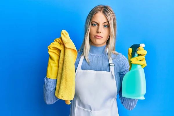 きれいなエプロンを身に着けている美しいブロンドの女性は 洗浄製品を懐疑的かつ神経を保持し 問題のために動揺を眉をひそめる 否定的な人 — ストック写真