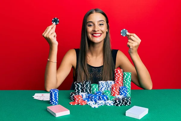 Νεαρή Ισπανίδα Που Κάθεται Στο Τραπέζι Κρατώντας Μάρκες Καζίνο Χαμογελώντας — Φωτογραφία Αρχείου