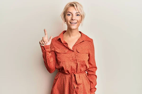 Młoda Blondynka Luźnych Ubraniach Uśmiechnięta Pomysłem Lub Pytaniem Wskazującym Palcem — Zdjęcie stockowe