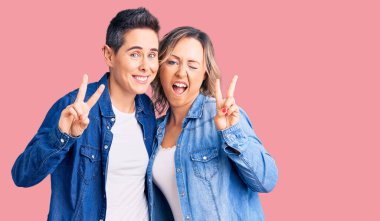 Gündelik kıyafetler giyen, gülen yüzlü, kameraya göz kırpan parmaklarıyla zafer işareti yapan iki kadın. İki numara.. 