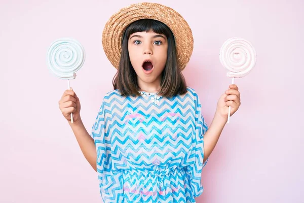 若いです女の子とともにバング身に着けている夏のドレス食べるキャンディー恐れと衝撃で驚きと驚きの表情 恐怖と興奮した顔 — ストック写真