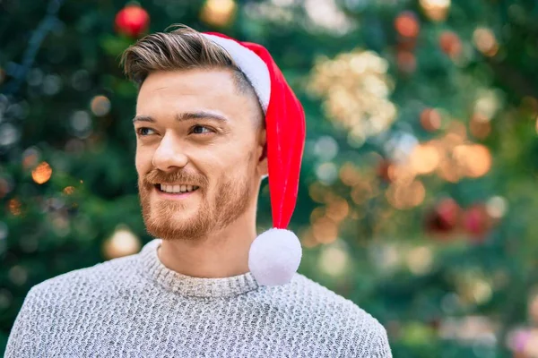 Νεαρός Καυκάσιος Άντρας Χαμογελάει Χαρούμενος Φορώντας Χριστουγεννιάτικο Καπέλο Στο Πάρκο — Φωτογραφία Αρχείου