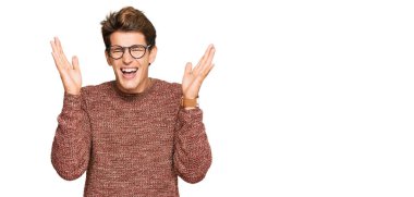 Sıradan süveter ve gözlük takan yakışıklı beyaz adam başarı için çılgın ve çılgın kutlamalar yapıyor kolları havada ve gözleri kapalı heyecanla bağırıyor. Kazanan konsept 