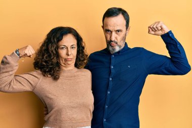 Orta yaşlı İspanyol çift gündelik giysiler giyiyor güçlü insan kol kası gösteriyor, kendinden emin ve gururlu güç sahibi. 