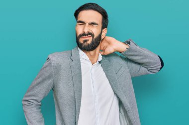 İş kıyafetleri giyen, boynu ağrıyan, elleriyle boynuna dokunan, kas ağrısı çeken genç İspanyol bir adam. 