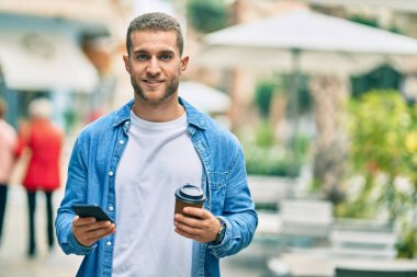 Kafkasyalı genç adam akıllı telefon kullanıyor. Şehirde kahve içiyor..